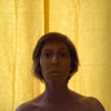 Rainbow Squared Year 5, Piece Nineteen: 17. Yellow Yellow. Animated loop of a yellow background lit from behind with ilyse in silhouette, then face moving forward to overexpose background and reveal ilyse’s face painted yellow.